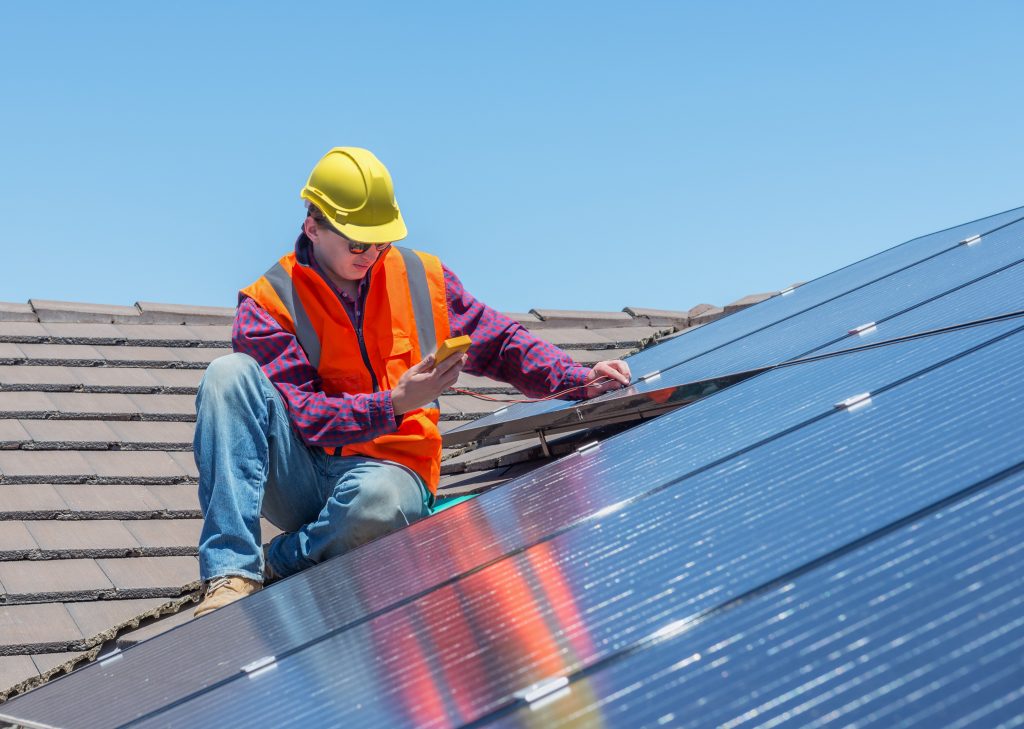 Man installing solar panels on top of a roof